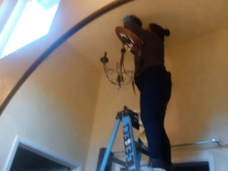 Electrician installing a chandelier in a La Habra residence